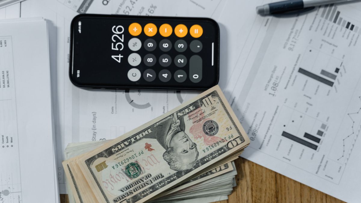 Dinero en efectivo y una calculadora, símbolo de honorarios de abogado. ¿Cómo saber si un caso te está saliendo rentable o estás perdiendo dinero? — Compuasociados.