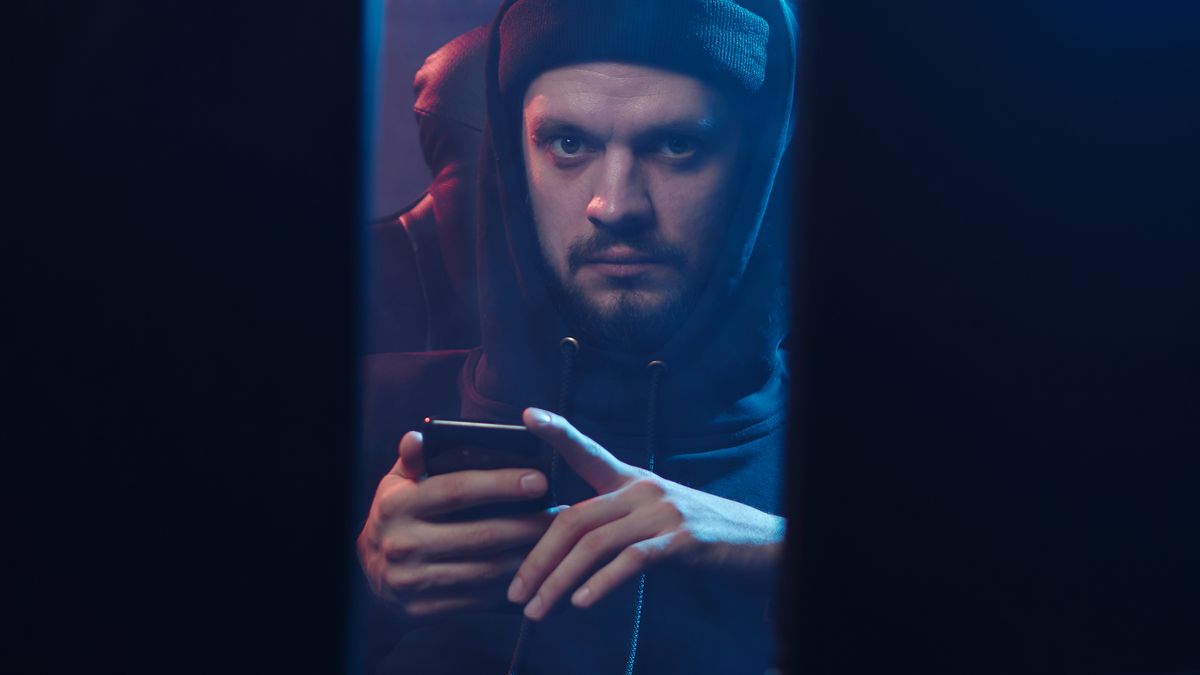 Persona en la penumbra usando un teléfono, símbolo de riesgo de manipulación de datos. Integridad de tus procesos: cómo detectar si modificaron o editaron algo — Compuasociados.