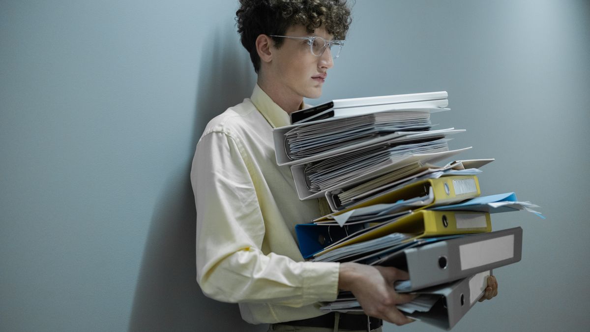 Abogado cargando una pila de carpetas y expedientes. ¿Cómo saber el estado de cada caso sin revisar carpeta por carpeta? — Compuasociados.